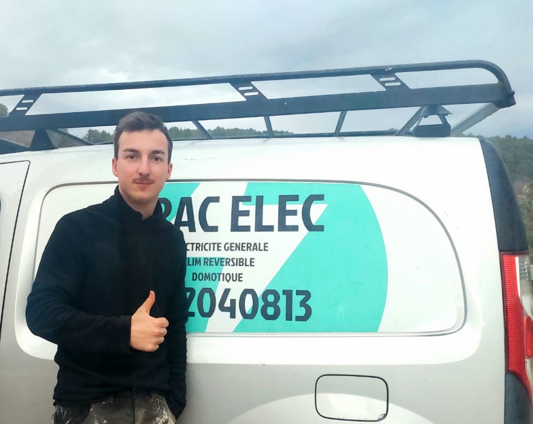 Maxime, artisan électricien Dignelec, devant son véhicule